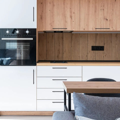Modern kitchen with matte black stainless steel cabinet handles set on wood and white cabinetry.