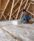 Woman installing Pro Grade R38 Unfaced Fiberglass Batts covering 341 Square Feet In An Eight Pack in attic.