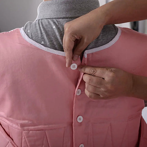 Person fastening buttons on Chenhon Criss Cross Chest Vest Restraint Secure Patient Safety For Bed Or Chair Use Adjustable Elastic Cotton Fabric.