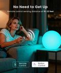 Woman using remote to control 8 Inch LED Night Light Ball With Remote, 16 RGB Colors, on table, showcasing its brightness and color.