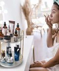 Woman applying skincare beside a Rotating Makeup Organizer 2 Tier Lazy Susan Trays, Clear Countertop Storage For Vanity, Skincare And Perfume Display.