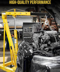Yellow hydraulic 2-ton shop crane with folding arms and 6 steel casters lifting a car engine in a workshop