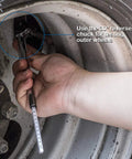Side view of a silver CZC Auto pencil tire pressure gauge with stainless steel stem testing a car tire valve on a wheel