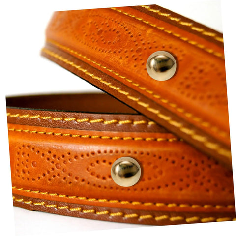 Close-up view of leather belt with golden studs and stitched edges.