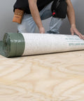 Real Deal 3 In 1 Flooring Underlayment Roll For Laminate And Engineered Wood shown being unrolled on plywood subfloor.