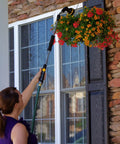 Woman using RelaxGrip No Sweat Eight Pattern Pivoting Head Watering Wand With Quick Connect Extension to water hanging plants.
