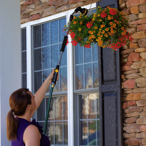 Woman using RelaxGrip No Sweat Eight Pattern Pivoting Head Watering Wand With Quick Connect Extension to water hanging plants.