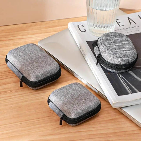 Compact Oval Tech Stash Organizer To Keep All Your Power Cords And Earbuds Straight Up Secure With A Rigid Hard Shell on a desk.