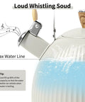 Close-up of Stovetop Tea Kettle 2.5 Quart Whistling Kettle With Stainless Steel Body Creamy White Finish Wood Pattern Folding Handle and max water line.