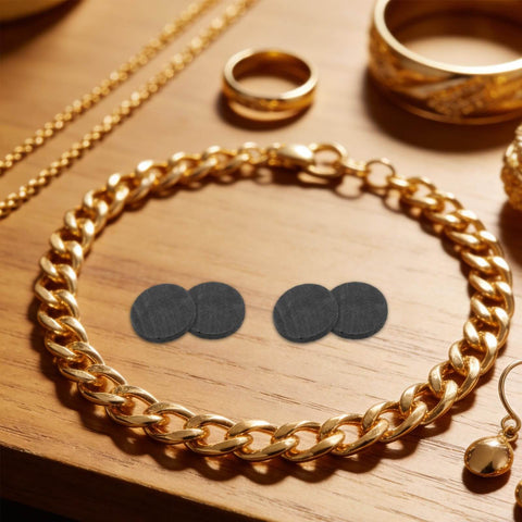 Round Graphite Electrode Plates For Melting And Electrolysis High Purity Graphite Disk Ingots on a wooden table with gold jewelry