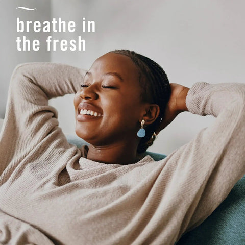 Person relaxing on couch, text 'breathe in the fresh', promoting Plug In Air Freshener Starter Kit With Odor Fighting Scented Oils.