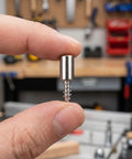 Close-up of a metal shelf peg from Self Tapping Shelf Peg Set for Cabinets and Laminate Shelves No Fuss Easy Install Includes 150 Shelf Pins and 150 Sleeves Heavy Duty Cabinet Hardware for Kitchen Bookcases Black held between fingers