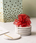 Dope White Marble Coasters Set Of 6 With Gold Brass Inlay For Luxury Aesthetic, tied with a red ribbon on a table
