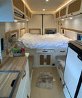 Interior view of an RV camper featuring rotating aluminum table legs for RV campers setup, with a kitchen and bedding.