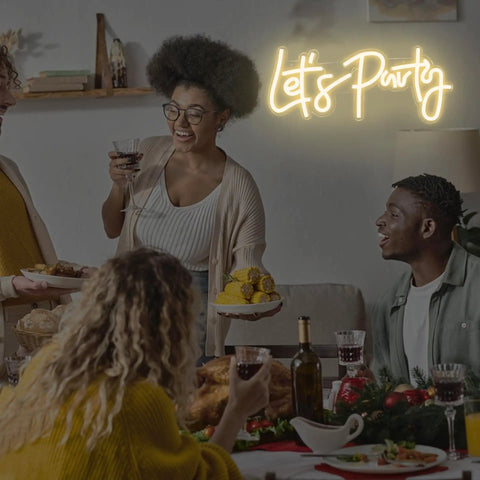 Group celebrating under Lets Party Neon Sign Dimmable LED Neon Light For Wall Decor 16x7 Inches Word Sign with warm white glow.