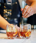 Bartender stirring drinks with bar spoon next to ice crackled by 9-Inch Ice Pick With Wood Non-Slip Handle And Safety Cover.
