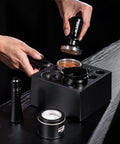 Top Shelf Espresso Barista Gear Featuring 54 Mm Stainless Steel Tamper Fits Breville Portafilters Includes Precision Wdt Needles Sleek Dosing Funnel And Two Hundred Premium Paper Filters To Nail That Perfect Morning Pull. Hands using a stainless steel tamper above a breville portafilter on a black wooden surface.