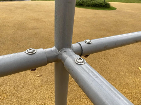 Close-up of stainless steel flat washers on a metal pipe frame cross joint.