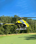 Ready To Fly Pro Grade RC Helicopter with dual brushless motors in flight, 6CH remote, outdoor 3D flight over grassy field.