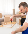 Person using a screwdriver for assembling furniture indoors.