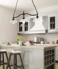 Farmhouse Chandelier Hanging Light Fixture In Rustic Black Metal With Three Bowl Shaped Clear Glass Shades over kitchen island
