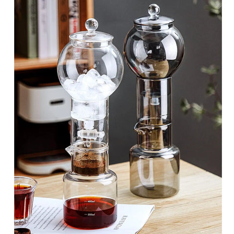 Premium Glass Cold Brew Drip Tower With Adjustable Flow Dripper For Smooth Cold Extraction Coffee Maker 600 Milliliter Gray Body on table with ice and brewed coffee.