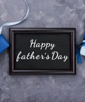 Framed 'Happy Father's Day' sign placed between gift boxes with ribbons, showcasing vinyl lettering design potential.