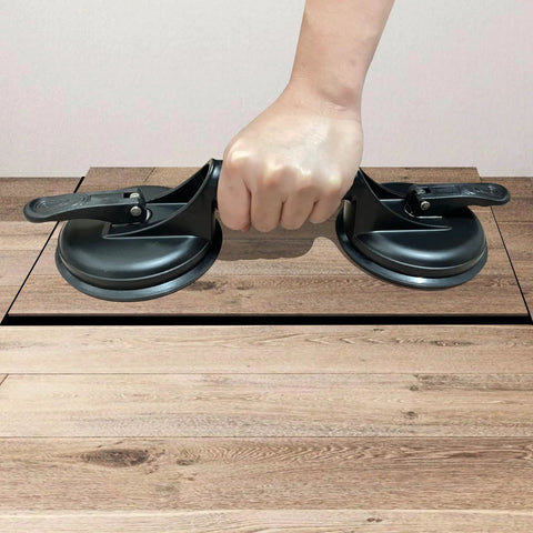 Hand using Floor Gap Fixer Tool For Laminate And Floating Floors With Suction Cup And Mallet on wooden surface