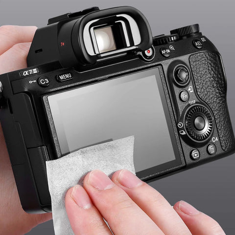 Back view of black mirrorless camera being cleaned with a white lint-free cloth.
