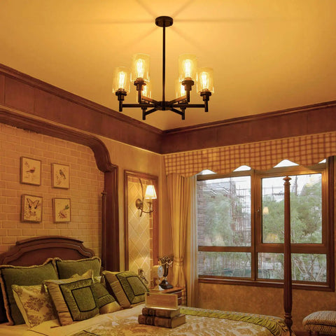Black Farmhouse Chandelier With Six Clear Glass Shades Hanging Over Dining Table Featuring Sturdy Metal Frame And Sleek Modern Design That Hits Different For A Killer Centerpiece Vibe In Any Home Space, in cozy bedroom setting.