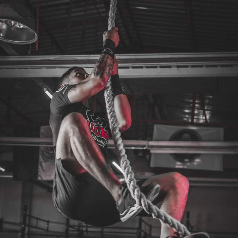 Man climbing on gym rope for strength training, using Outdoor Climbing Rope For Fitness And Strength Training, 1.5 Inch Gym Rope.
