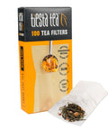 Box of 100 Disposable Loose Leaf Tea Filters For Easy Brewing with a single unbleached paper sachet next to loose tea leaves.