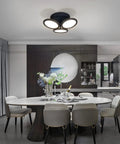 Modern dining room with elegant decor and sleek black circular ceiling light fixture with three illuminated round shades.