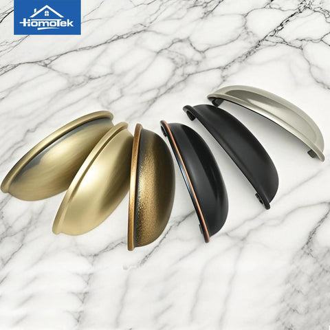 Various metal cup drawer pulls displayed on marble, including Matte Black Cup Drawer Pulls Five Pack for Cabinets and Furniture Dressers, 3 Inch Hole Centers Cup Handles