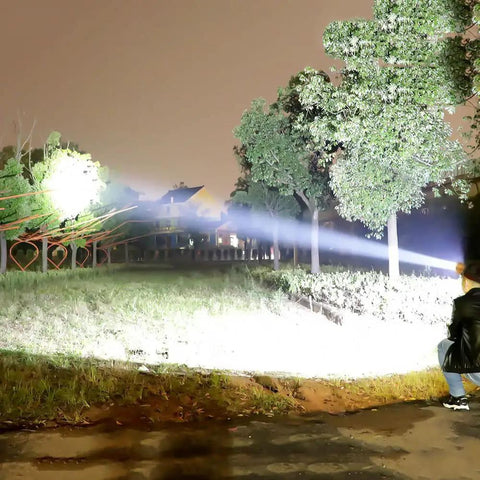 Person using Beast Mode Bright 90000 Lumen Hunting Headlamp With 9 Core Wide Beam, illuminating trees at night on a grassy field.