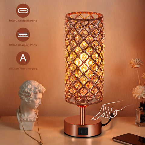 Rose Gold Crystal Table Lamp With 3 Way Dimmable Touch Control And USB C And USB A Ports, lit on a bedside with charging icons.