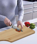 11x5 inch bamboo cutting board with handle on kitchen counter; person slicing red bell pepper.