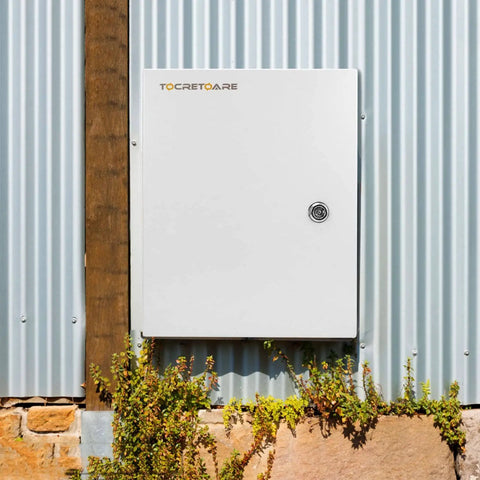 Rugged Outdoor Electrical Box With Lock And Mounting Plate Heavy Duty Steel Junction Enclosure 12 By 10 By 6 Inches NEMA 4X IP66 Waterproof Dustproof Weatherproof Project Box Built To Last For Tough Outdoor Installations installed on a corrugated metal wall with plants below.