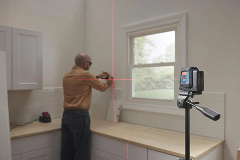 Man using GLL50-20 50 Ft Self Leveling Cross Line Laser With Integrated Magnetic Mount And Battery Flexibility For Quick No Hassle Setup On Any Jobsite Weather Tough IP55 Rated in kitchen.