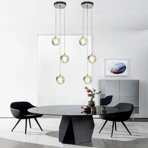 Three Light Bubble Orb Pendant With Chrome Finish Crystal Raindrop Cluster Chandelier installed above dining table.