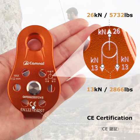 Orange zipline pulley for rescue, climbing, and hauling featuring load capacity markings, in a hand, showing CE certification details.