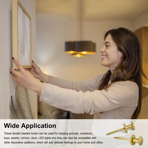 Woman hanging picture frame on wall using Heavy Duty Double Headed Picture Hangers And Thumb Tacks Pack Of Fifty Pieces For Hassle Free Wall Mounting With A Rock Solid Grip Perfect For Framed Photos Posters Artwork And Office Decor That Definitely Nails It.
