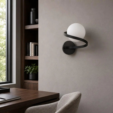 MAHGNTKCX Black Wall Sconce with Opal Glass Globe and Spiral Metal Frame mounted on a wall beside a desk.