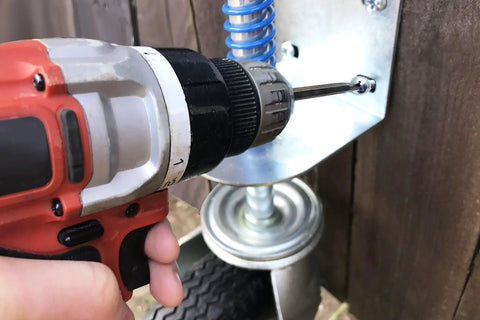 Installation of 8 Inch Pneumatic Spring-Loaded Gate Caster Wheel, 360 Degree Swivel, on a wooden gate with drill.