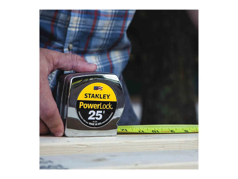 Person using Power Return Rule Tape Measure 25 Foot Yellow With Locking Blade, Powerlock II style, on wooden surface