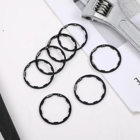 Seven Piece Grooved Hub Washer Set for Bikes, Cassette Spacers and Flywheel Headset Spacers, arranged on paper with wrench