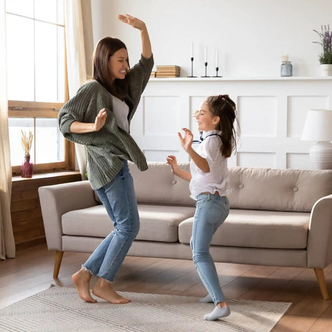 Mother and daughter dancing on a rug using 8 Pack Rug Gripper Pads For Hardwood Floors No Damage Non Slip For Area Rugs Reusable Carpet Tape.