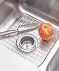 Stainless Steel Sink Grid With Center Drain Polished Finish For Kitchen Use Tough As Nails Heavy Duty Protective Rack That Prevents Scratches Doubles As A Draining Tray And Drying Rack Fits Most Standard Sinks with knife and apple on grid