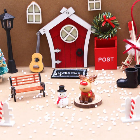 Christmas-themed miniature scene with tiny park street bench, guitar, snowman, reindeer, and red post box, dollhouse decor.