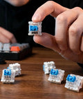 Blue 3-Pin Clicky Mechanical Keyboard Switches 50gf Actuation, Tactile And Audible Feedback, 30-Piece Bulk Pack For DIY Keyboards, Gaming, Typists, And Fidget Enthusiasts held in hand